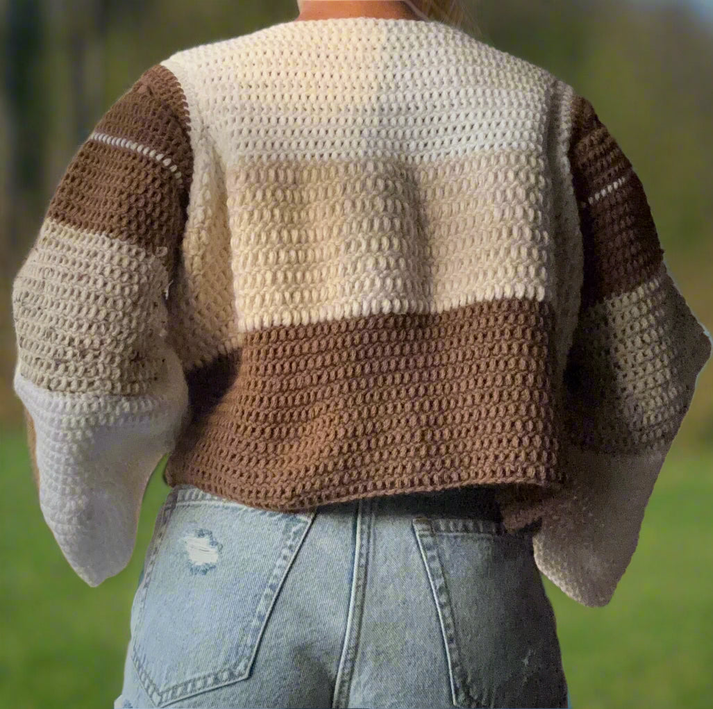 girl wearing a color-block sweater. the neckline begins with white, then turns to beige, then brown on the body of the sweater. The sleeves descend from brown to beige to white. 