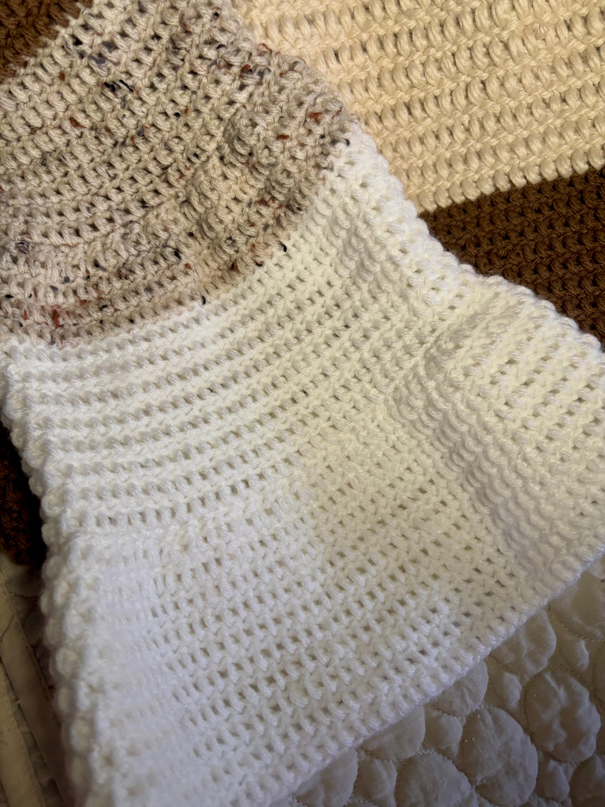 A color-block sweater laying flat. the neckline begins with white, then turns to beige, then brown on the body of the sweater. The sleeves descend from brown to beige to white. 