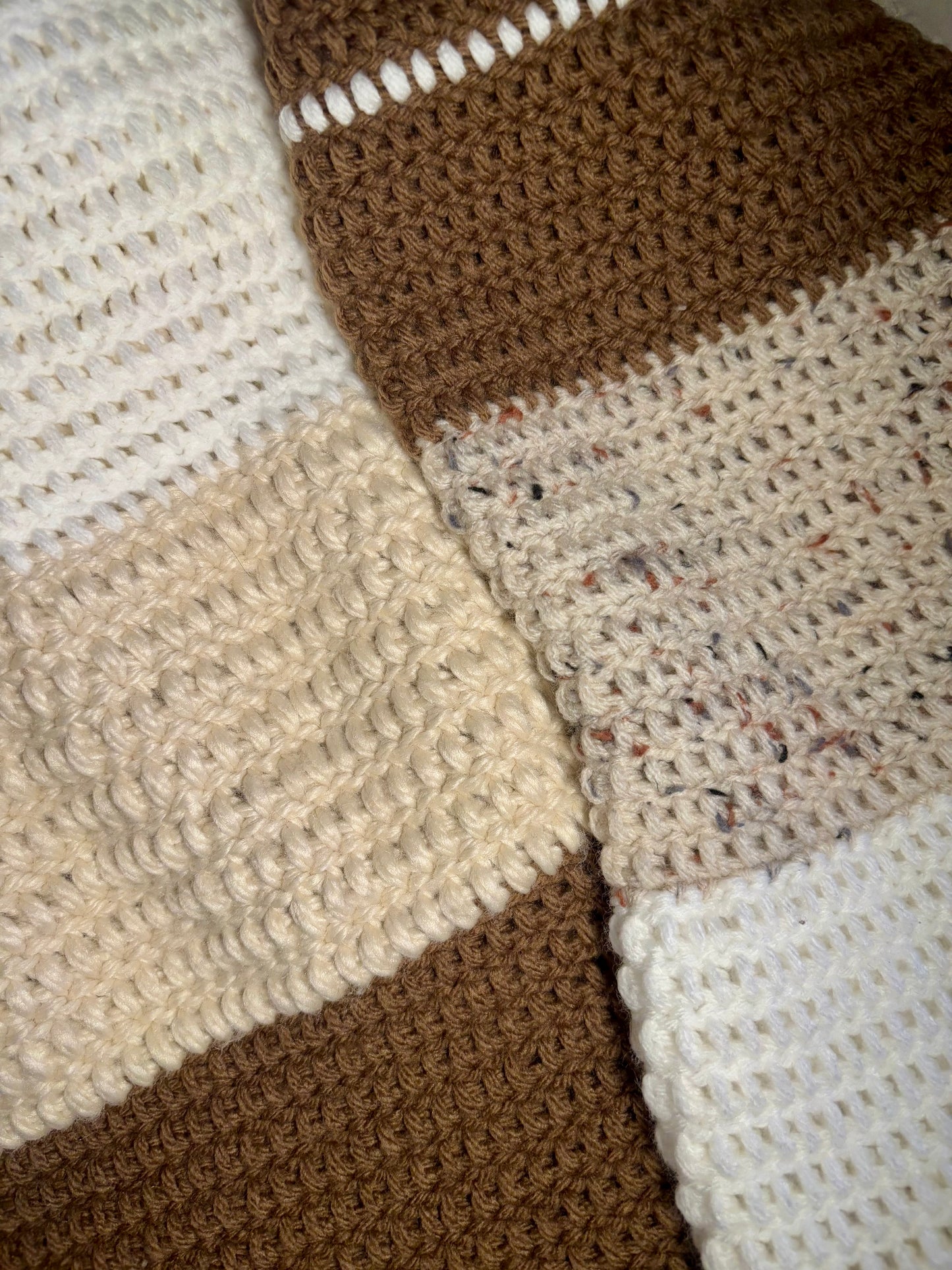 A color-block sweater laying flat. the neckline begins with white, then turns to beige, then brown on the body of the sweater. The sleeves descend from brown to beige to white. 