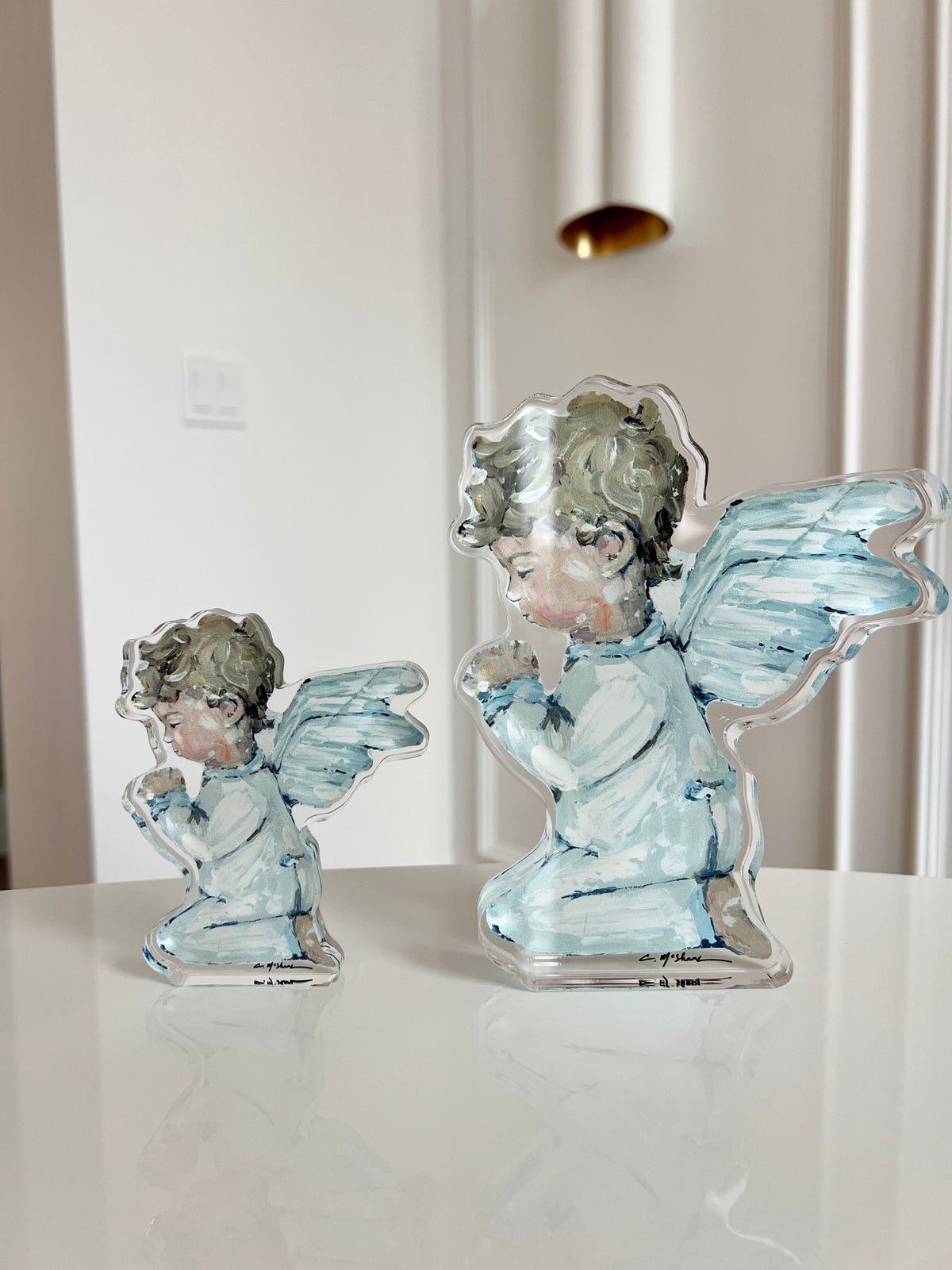 Two angel figurines on a white surface with a neutral background