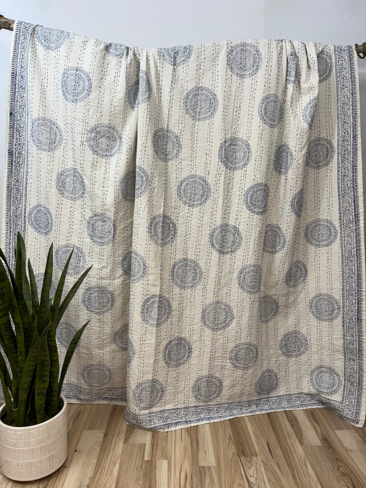 Patterned blanket draped over a chair with a plant on a wooden floor