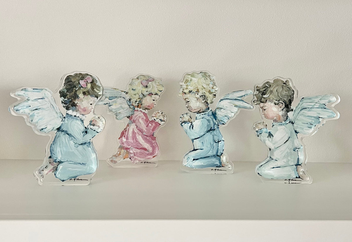 Four small angel figurines with translucent wings and painted bodies, arranged on a white shelf against a light beige wall.