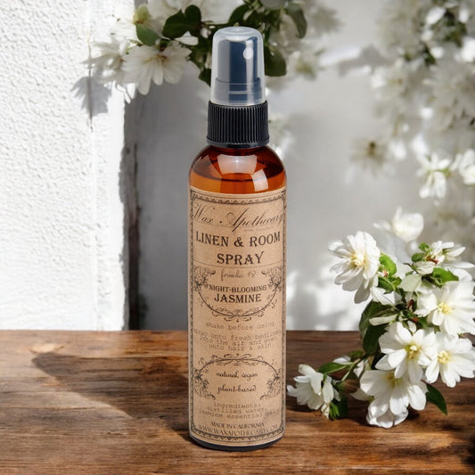 Linen & Room Spray bottle with floral label on a wooden surface with flowers in the background