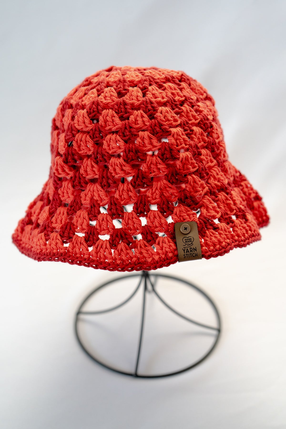 Red crochet hat on a stand against a light background