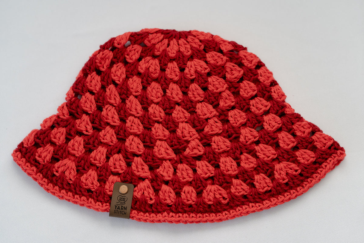 Red crochet hat with a visible brand label on a light gray background