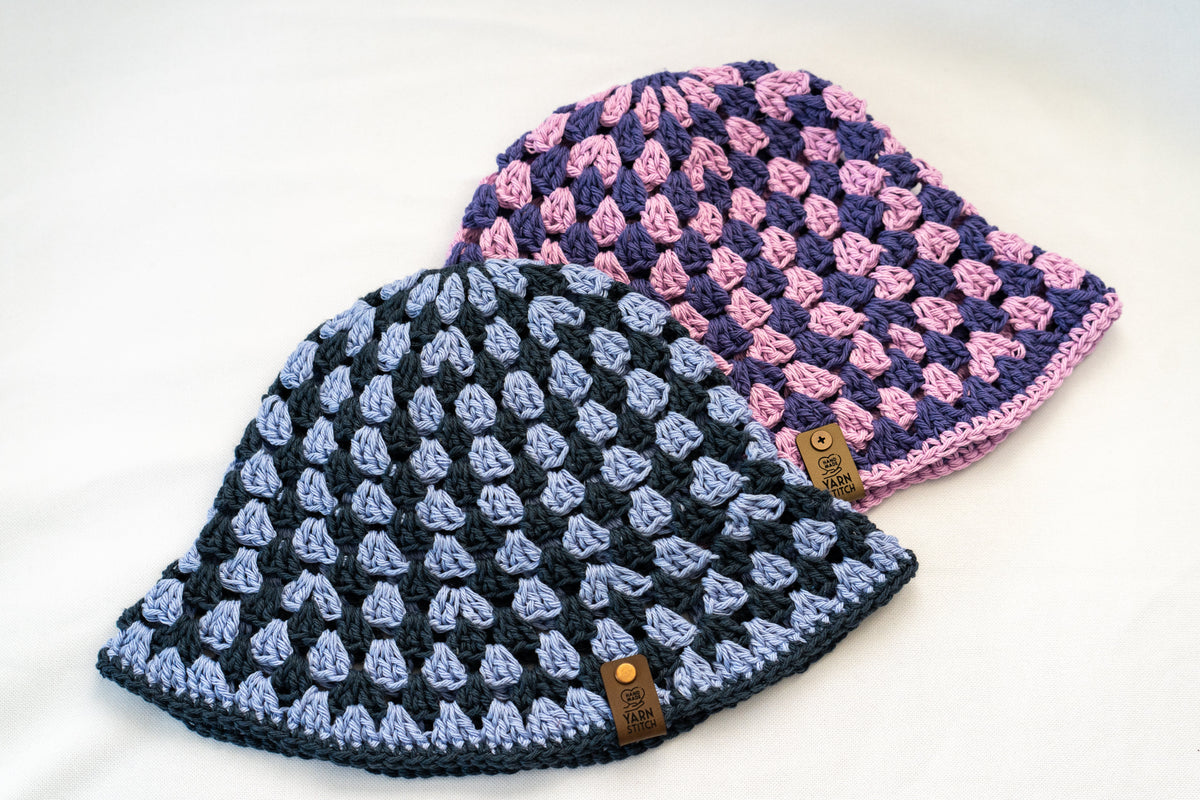 Two crocheted beanies, one blue and one pink, on a white background.
