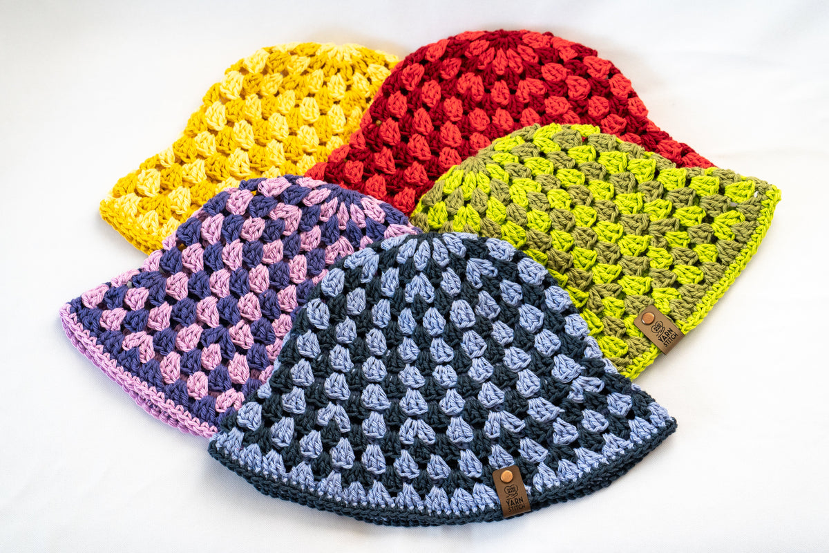 Five crocheted hats in different colors on a white background