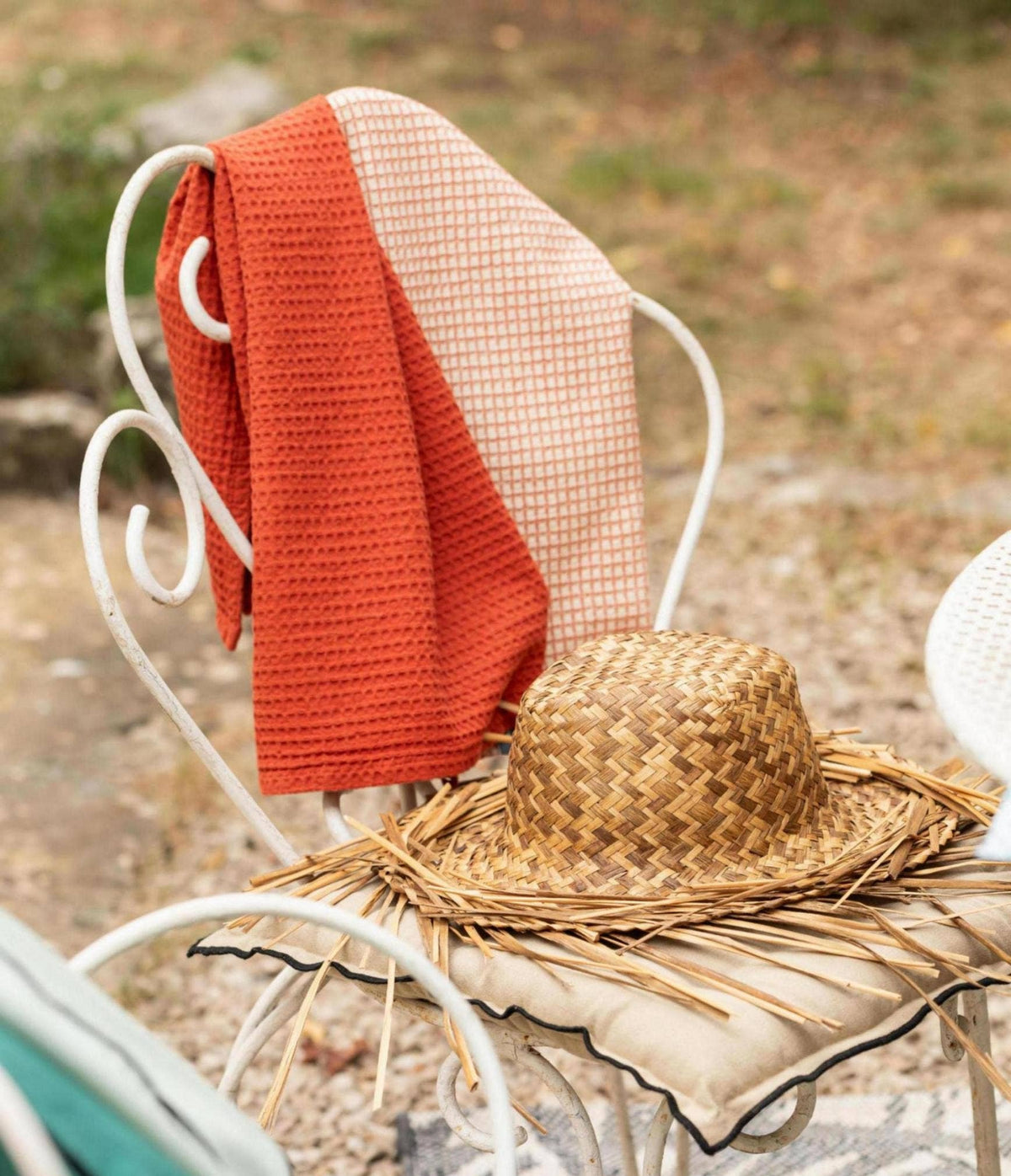Woven chair with a red blanket and straw hat on a blurred natural background