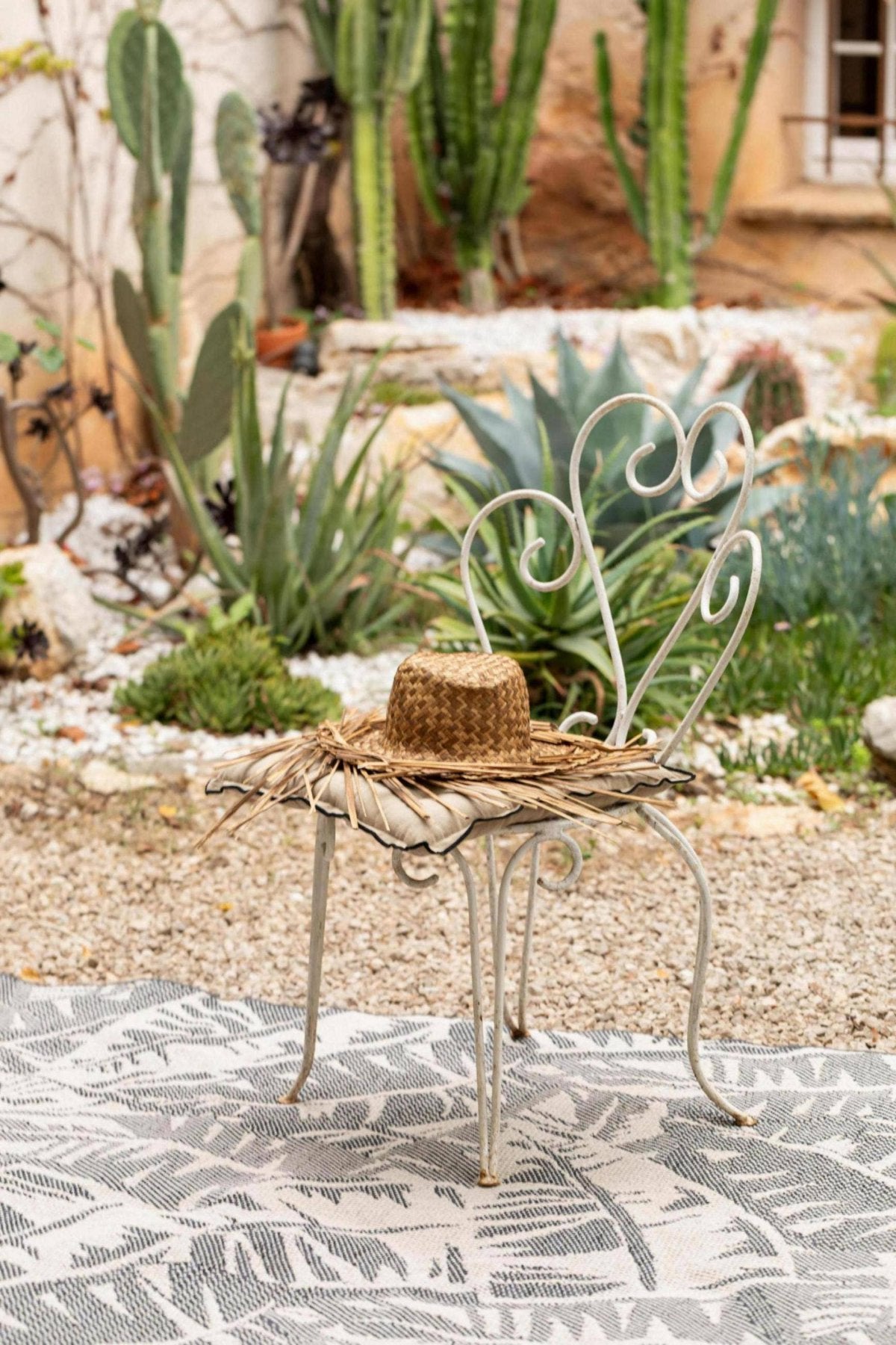 Small ornate metal table with a woven basket on a patterned rug outdoors.