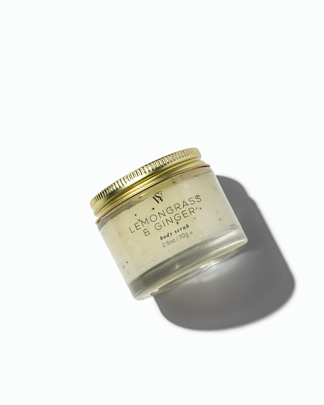 Jar of 'Lemongrass & Ginger' body scrub with a gold lid on a white background