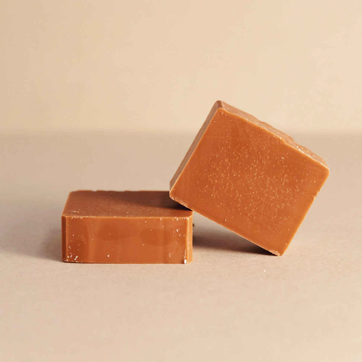 Two brown soap bars on a beige background