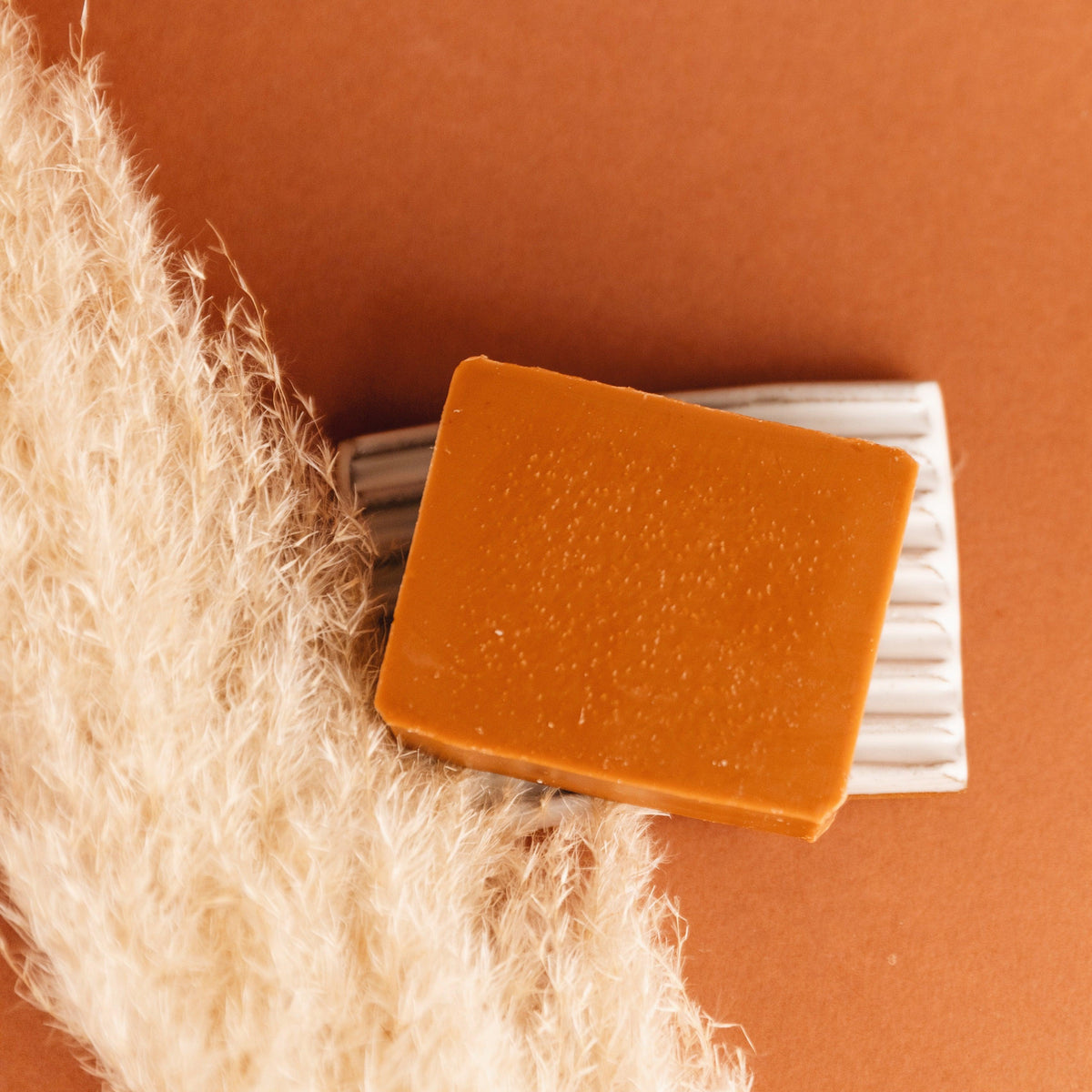 Orange soap bar with a white bar of soap on a textured orange surface