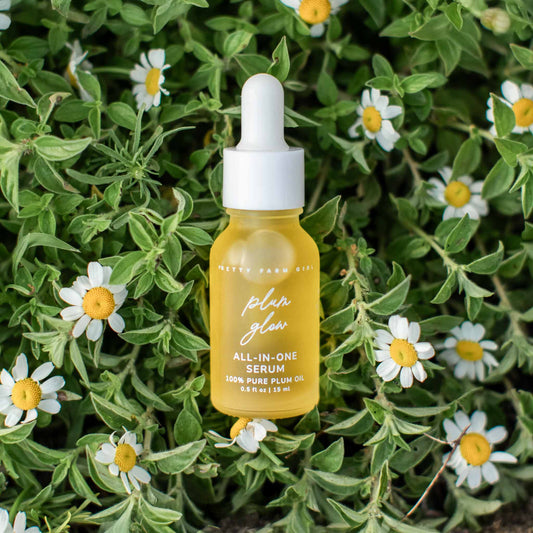 Yellow serum bottle with dropper on green leaves and flowers