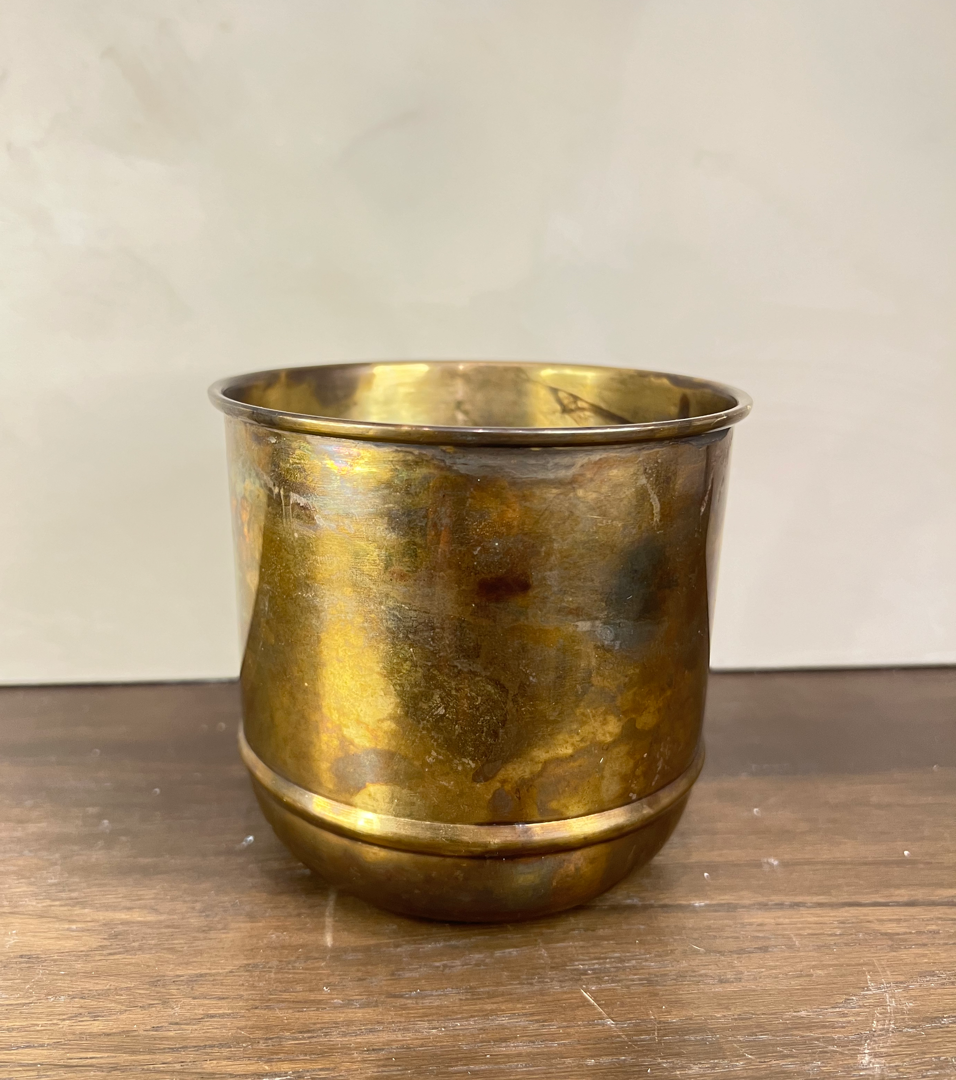 Brass cup on a wooden surface with a plain background
