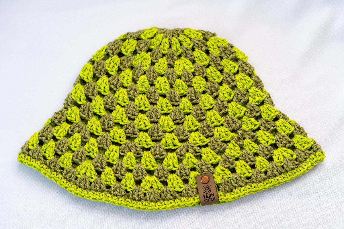 Crocheted beanie with green and yellow pattern on a white background