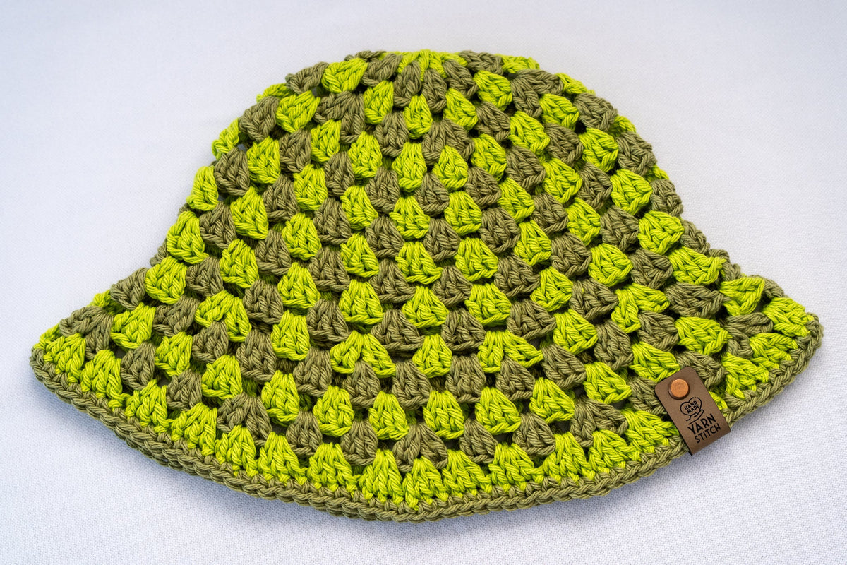 Crocheted hat with a green and yellow pattern on a white background