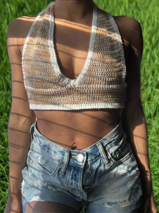 A crochet halter top with multicolored stripes, worn by a person standing in a grassy field.