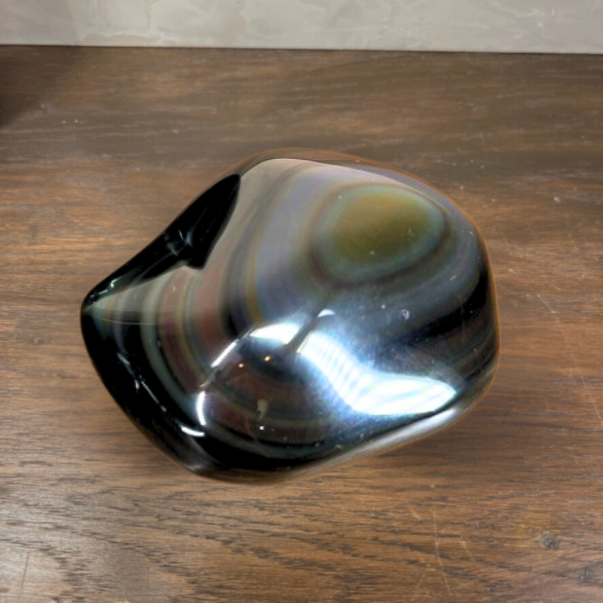 Polished stone with concentric color patterns on a wooden surface