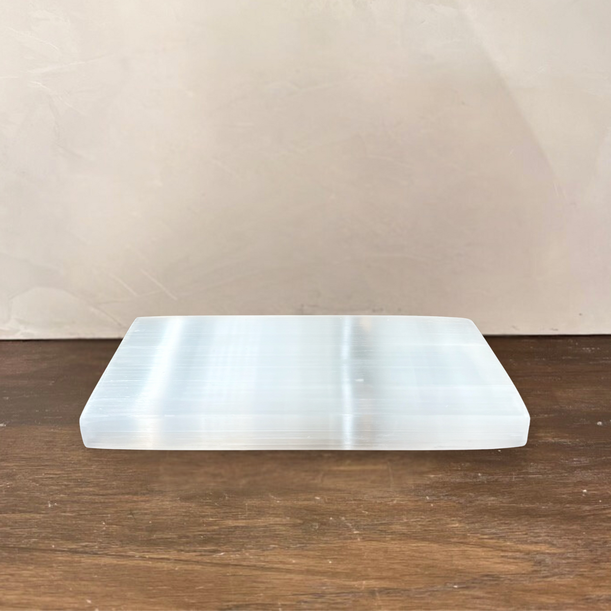 Rectangular white stone on a wooden surface with a beige wall background