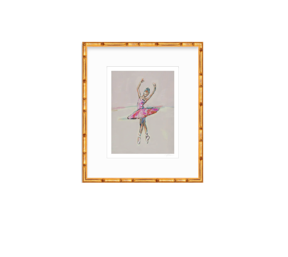A framed art print featuring a watercolor sketch of a ballerina in a pink tutu on a light gray background, enclosed in a white mat and a gold-toned bamboo-style frame.