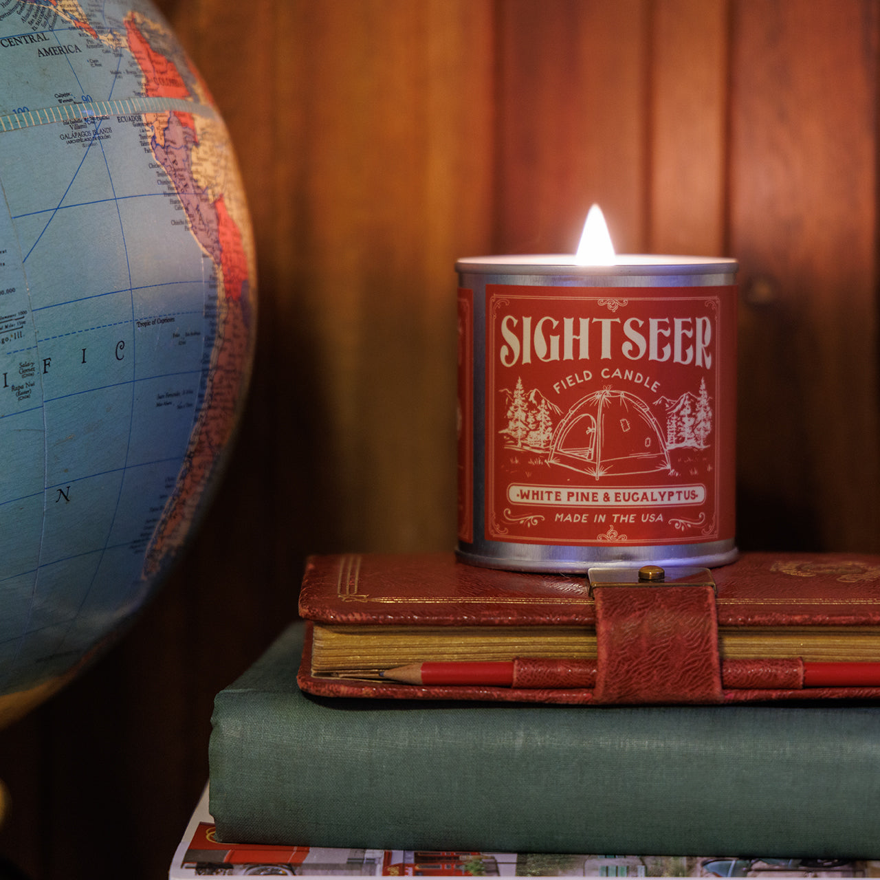 Sightseer candle on books with a globe in the background