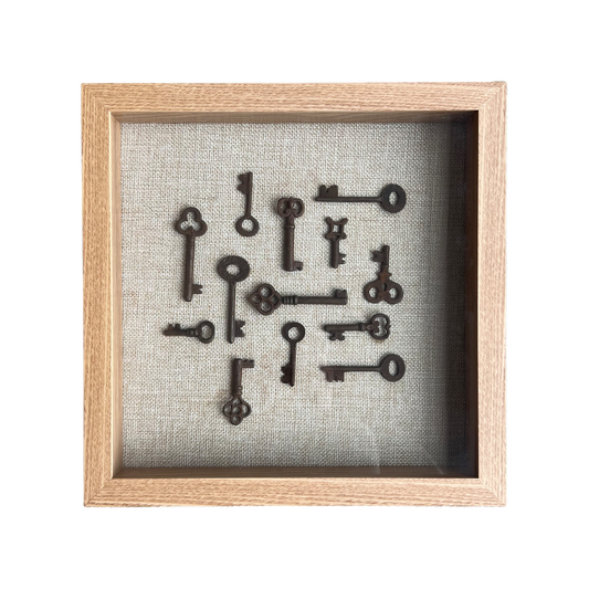Framed collection of vintage keys on a textured gray background