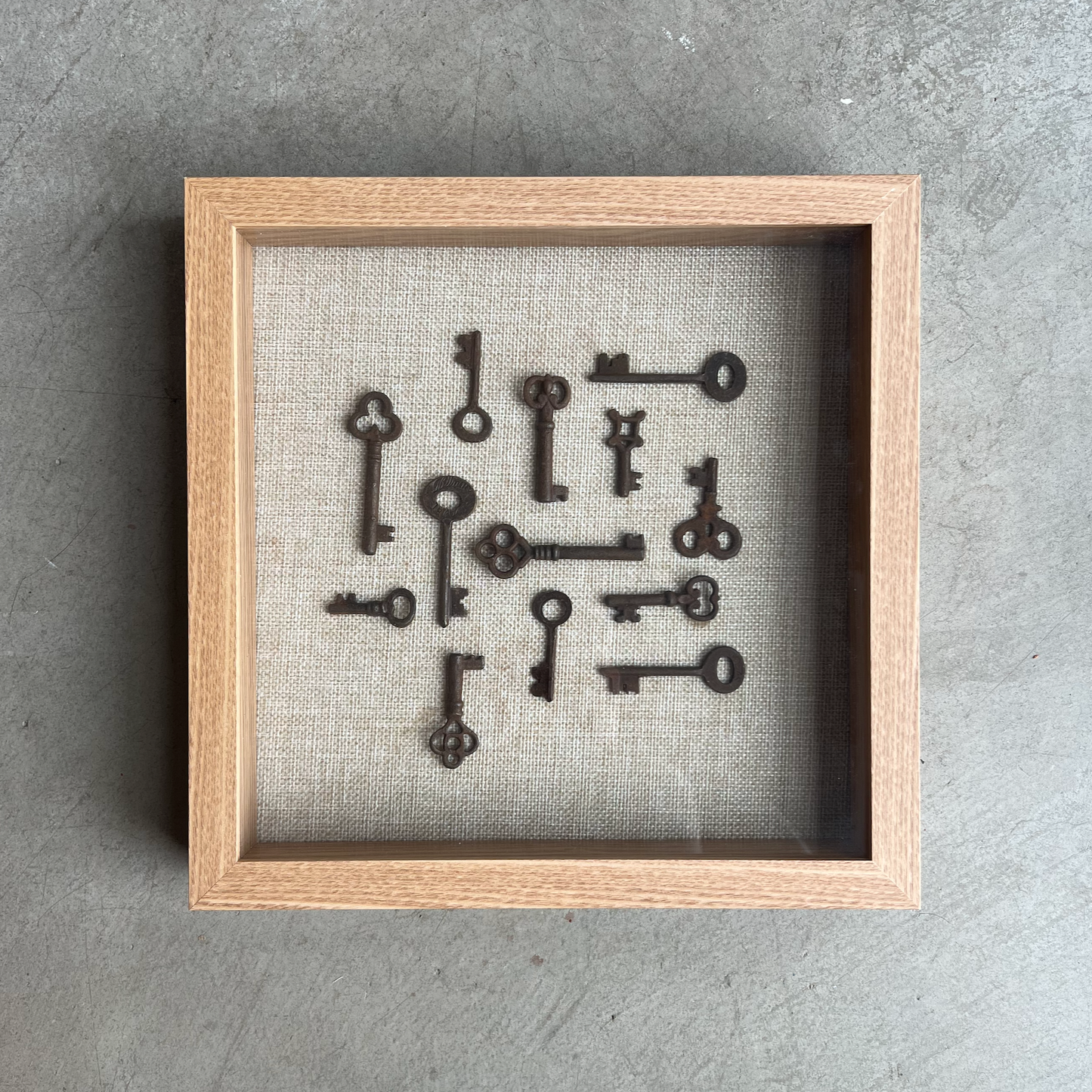 Framed collection of vintage keys on a textured gray background