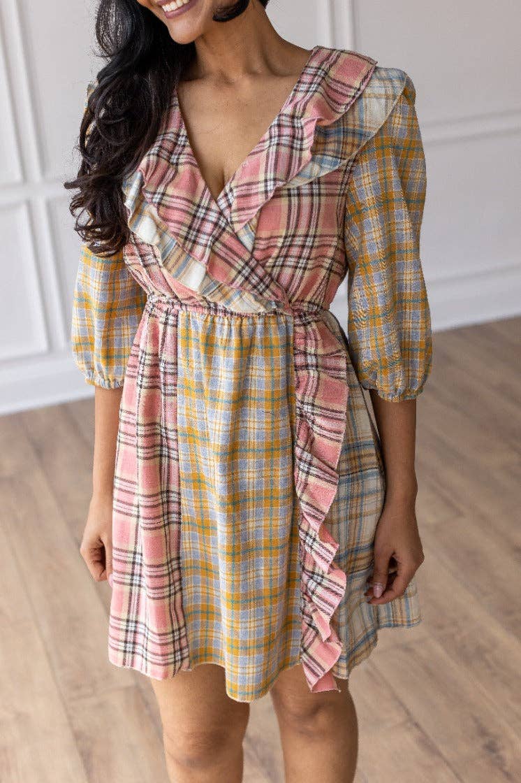 Woman wearing a plaid dress with ruffled sleeves on a wooden floor.