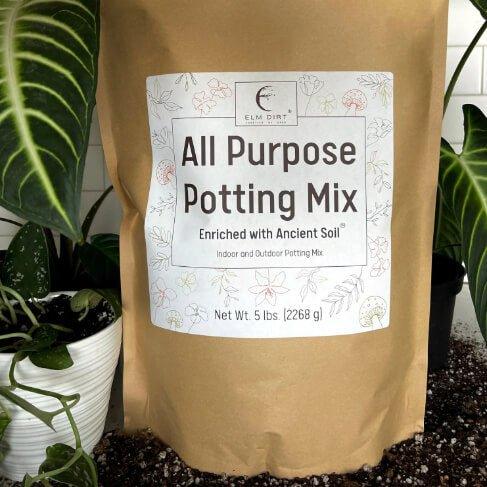 Bag of Elm Dirt All Purpose Potting Mix with plants in the background