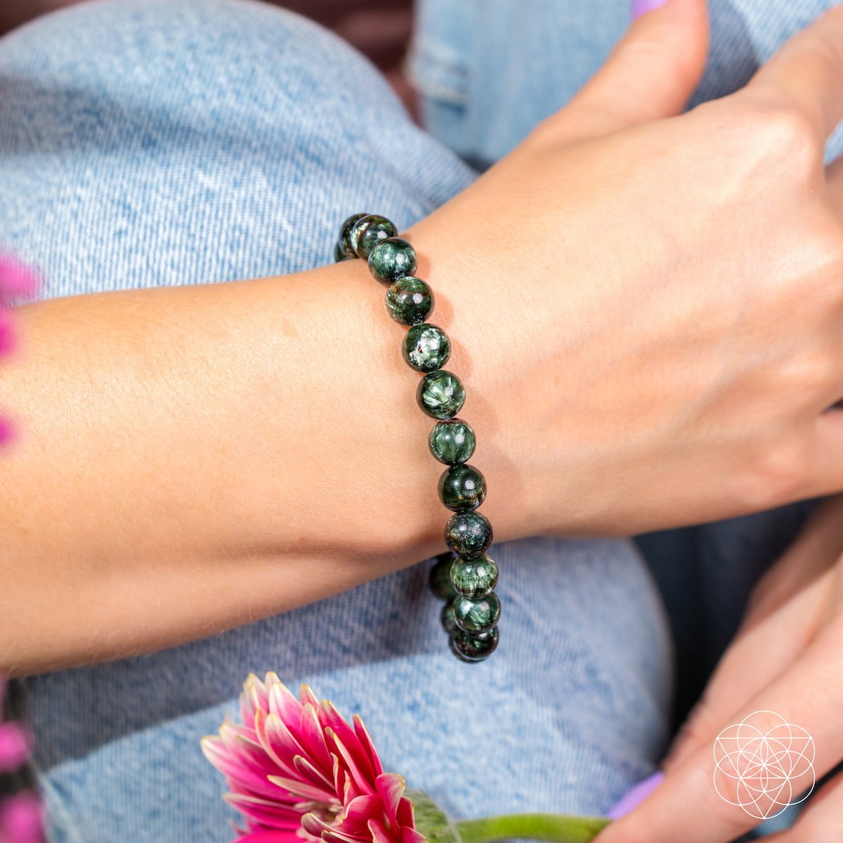 Person wearing a green beaded bracelet with a blurred background