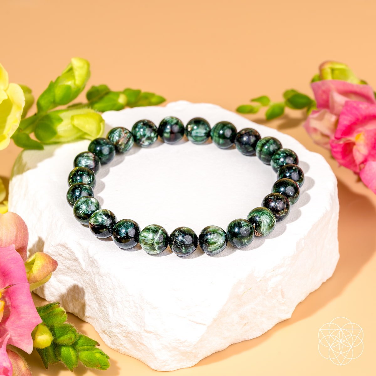 Green beaded bracelet on a white stone with flowers in the background