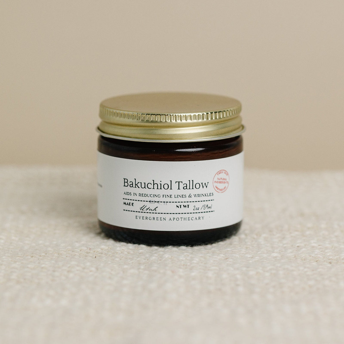 Jar of Bakuchiol Tallow on a textured surface with a beige background