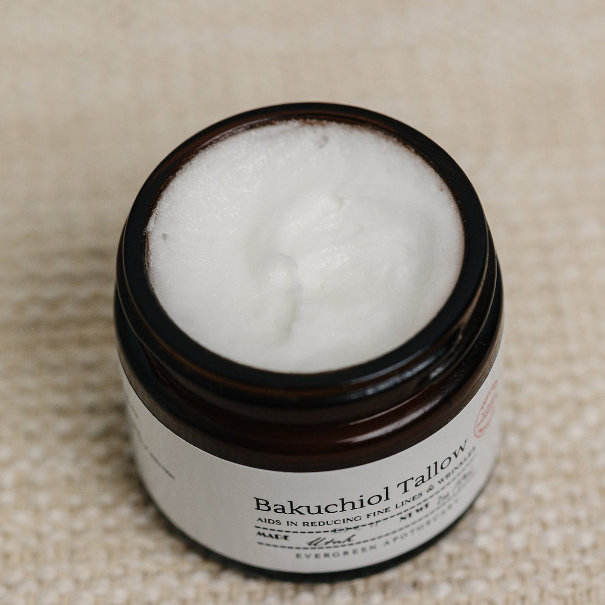 Jar of Bakuchiol Tallow cream with a beige background