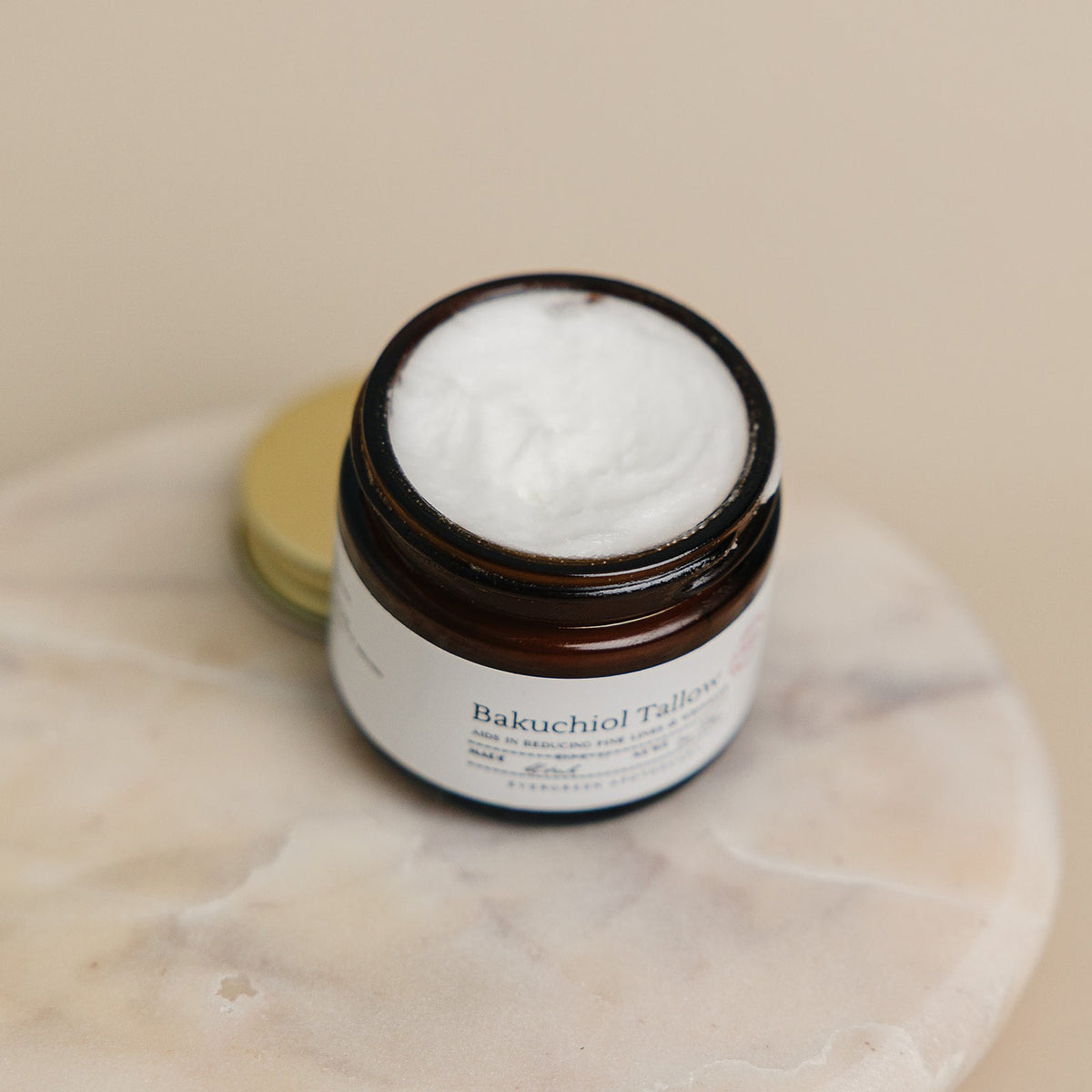 Jar of Bakuchiol Tallow cream on a marble surface