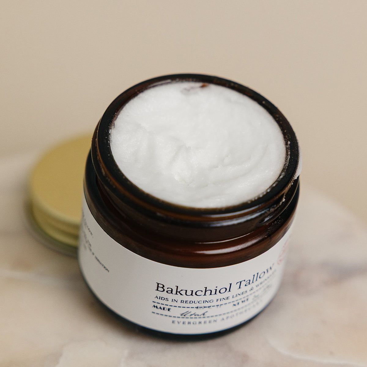 Jar of Bakuchiol Tallow cream on a marble surface