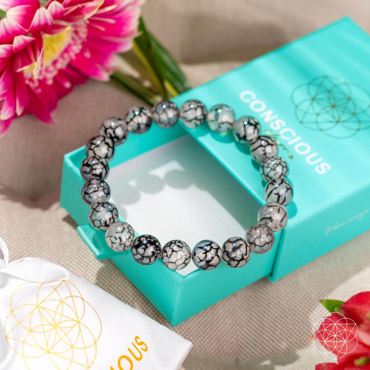 Bracelet on a turquoise box with pink flowers in the background