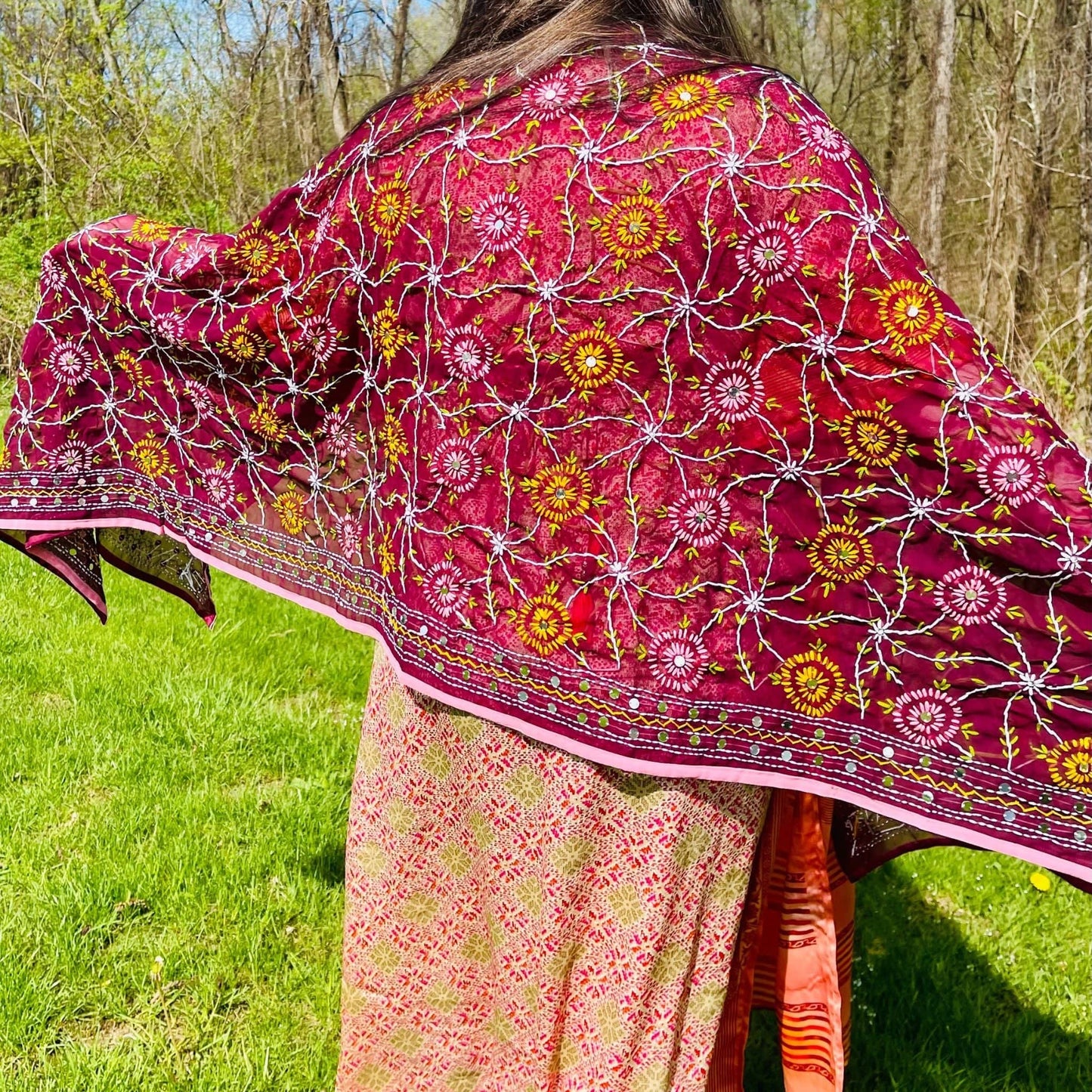 Person wearing a vibrant floral-patterned dupatta outdoors on a grassy area.
