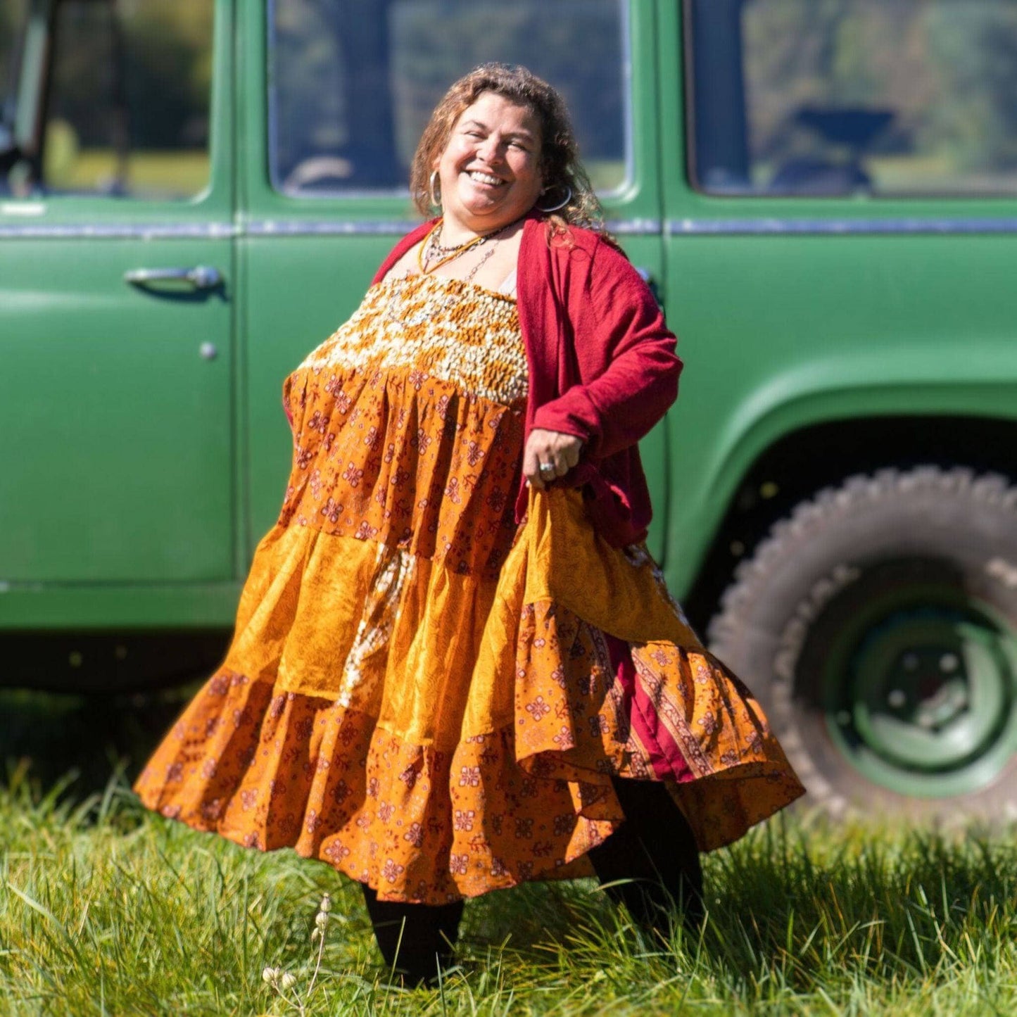 Woman in a yellow dress standing in front of a green vehicle