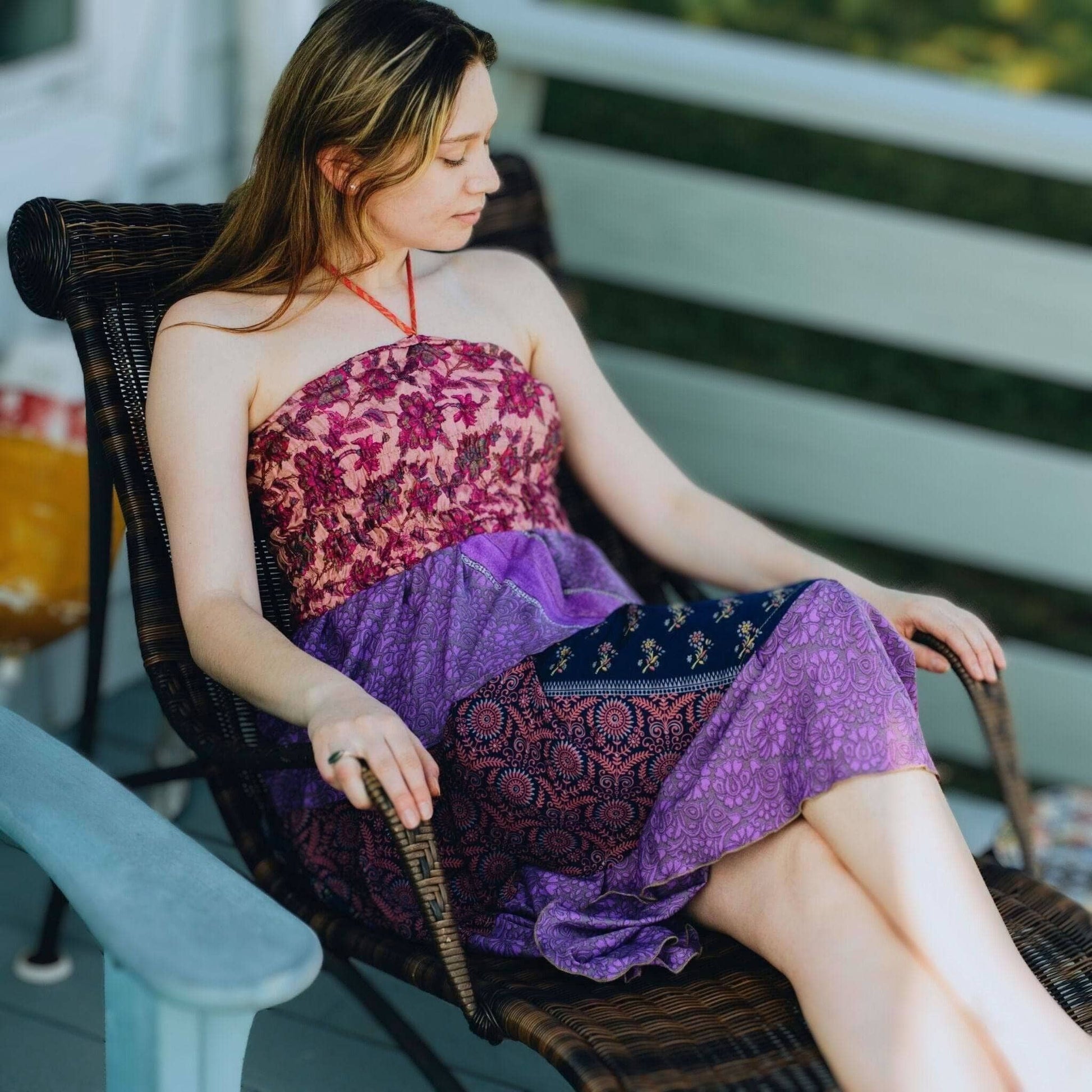 Woman sitting on a chair wearing a colorful dress with a patterned design.