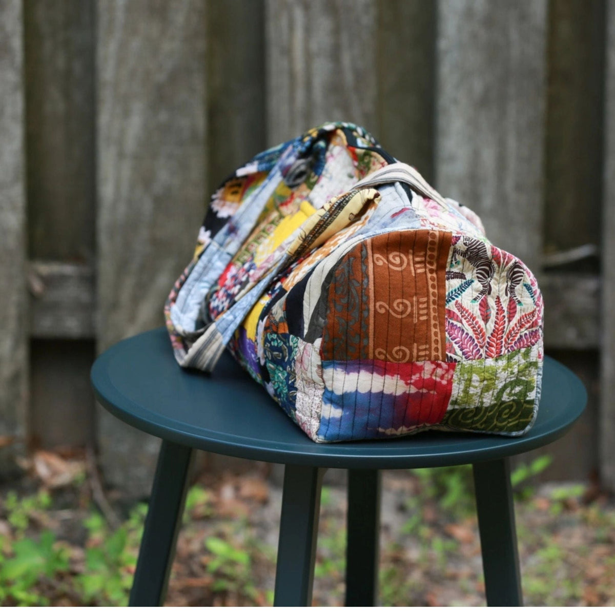 Colorful patchwork bag on a green stool outdoors