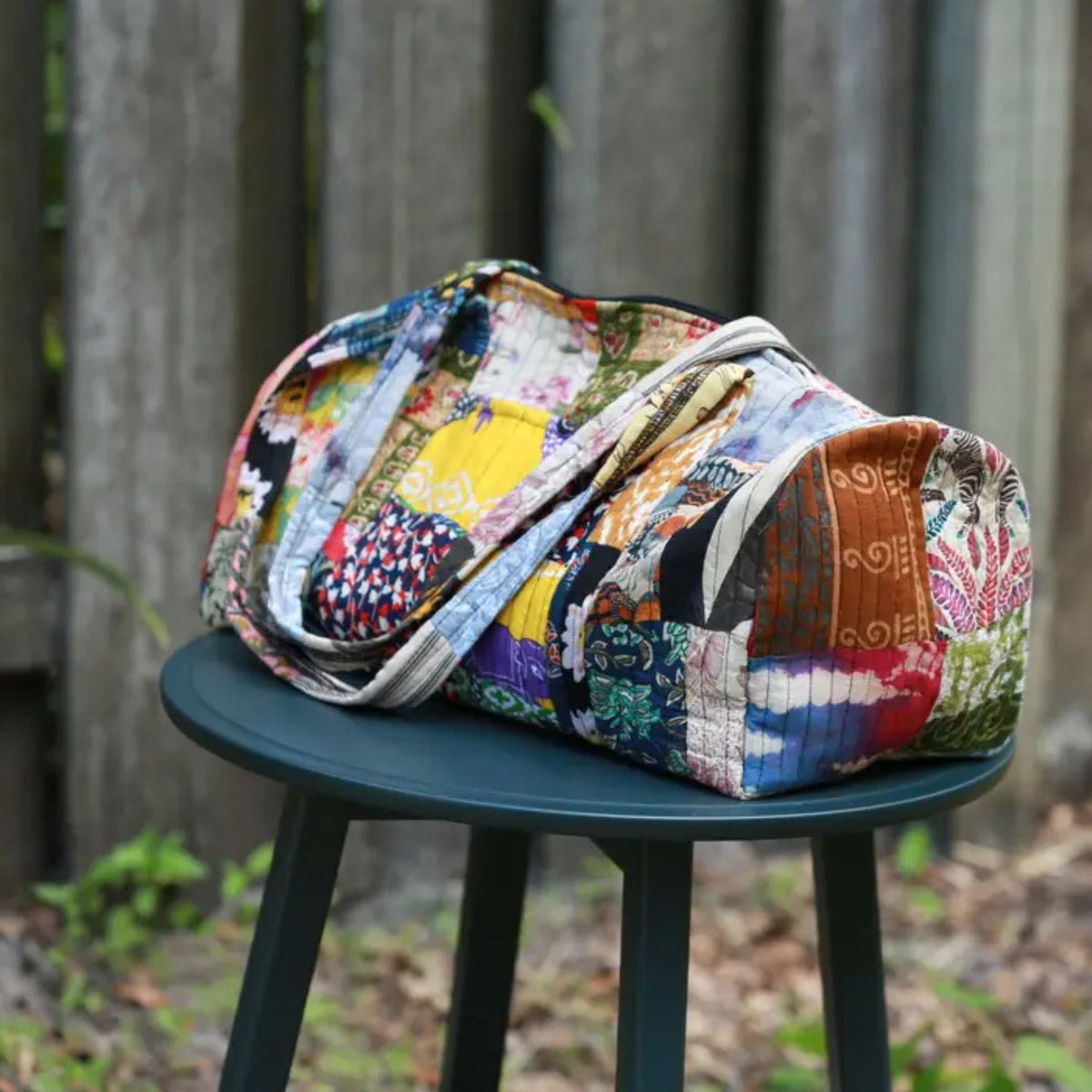 Colorful patchwork bag on a green stool outdoors