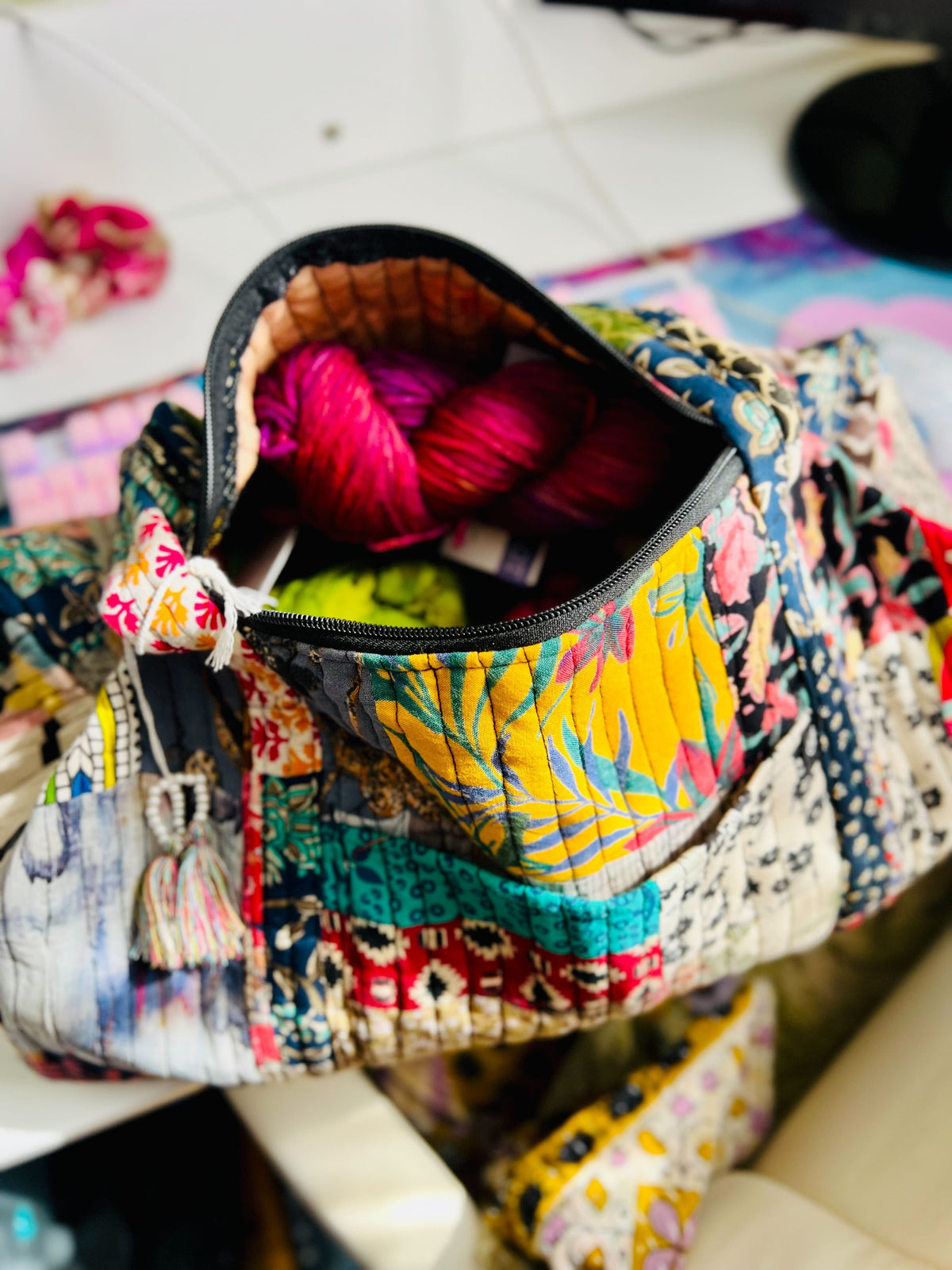 Colorful patterned bag with a zipper open, revealing pink and yellow items inside.