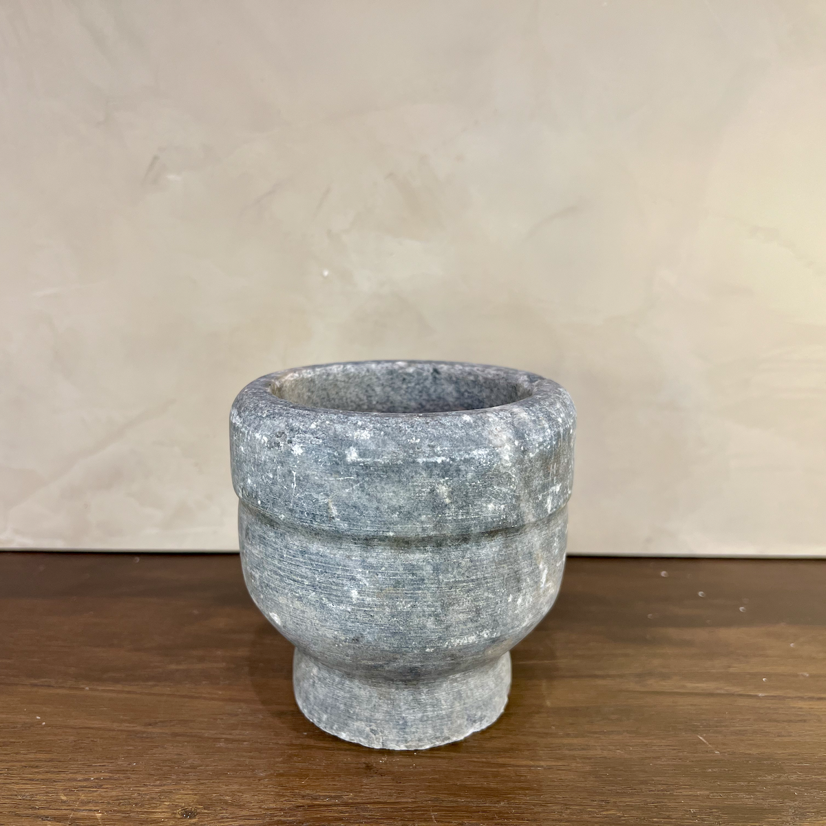 Stone mortar on a wooden surface with a beige background