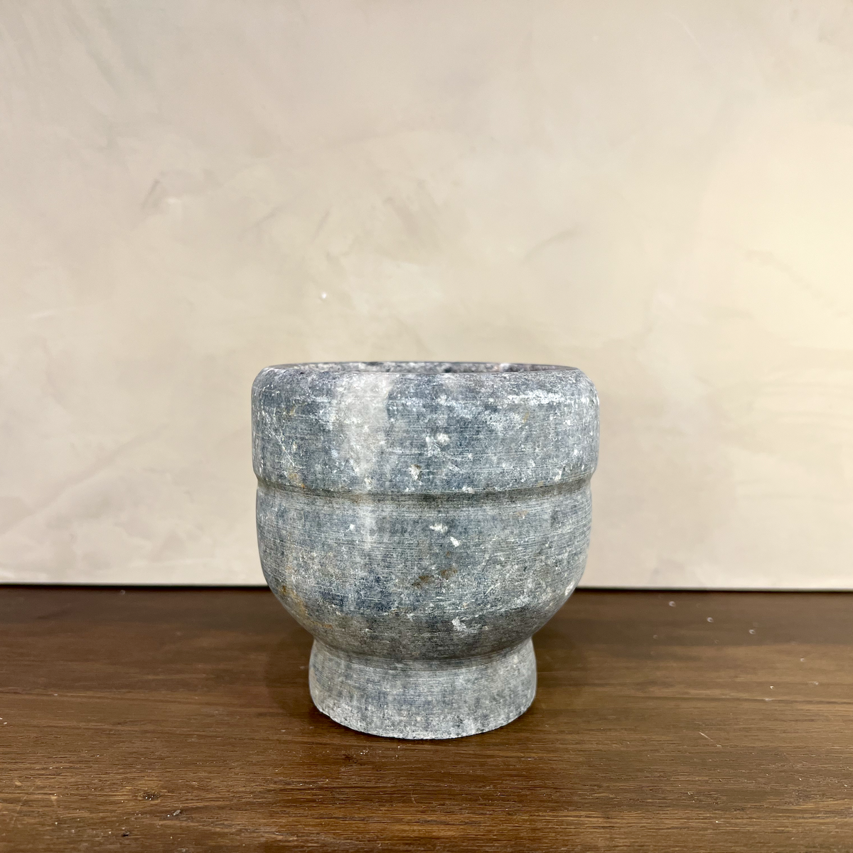 Marble-like stone bowl on a wooden surface with a neutral background
