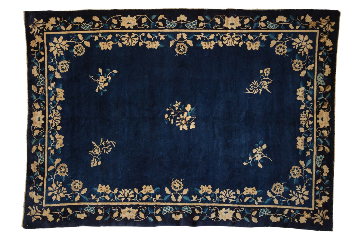 Navy blue rug with gold floral patterns on a white background