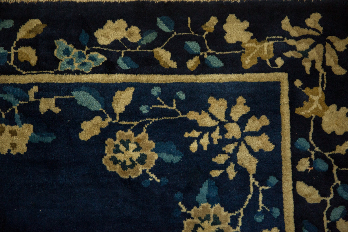 Close-up of a dark blue rug with gold floral patterns