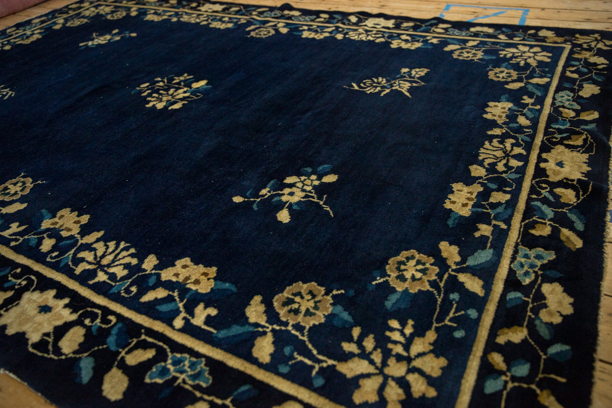 Navy blue rug with gold floral patterns on a wooden floor.