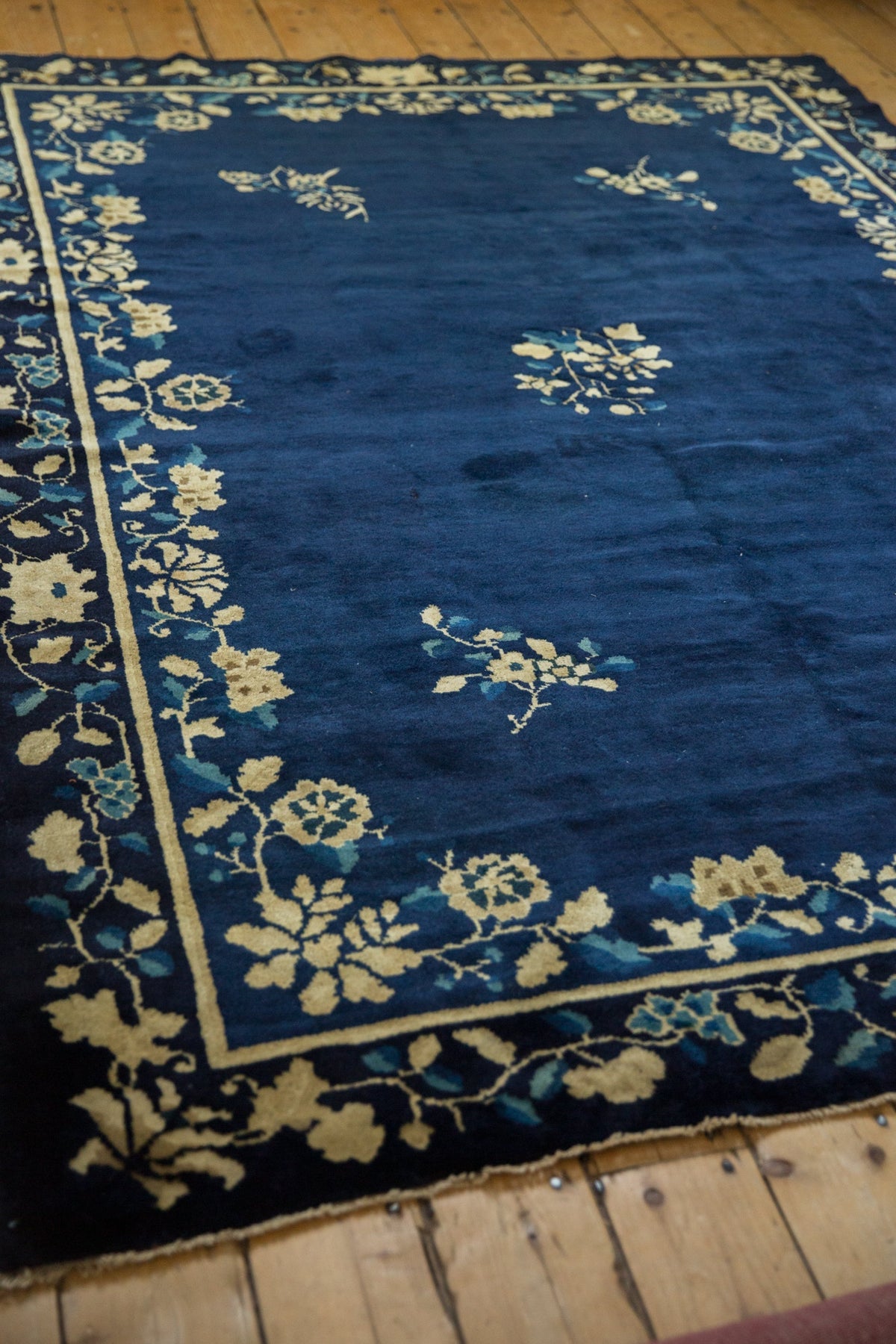 Blue rug with white floral patterns on a wooden floor