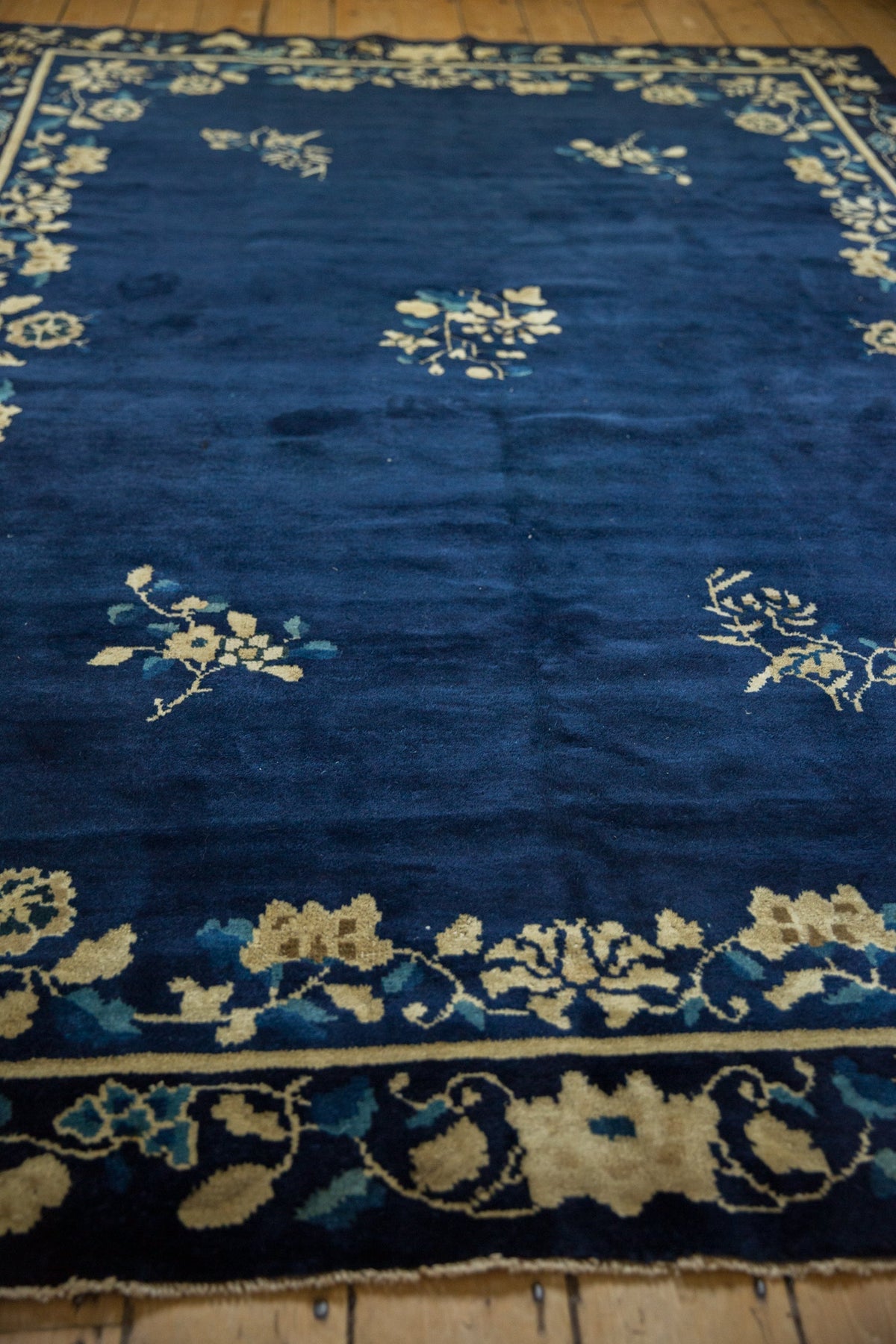 Blue rug with white floral patterns on a wooden floor
