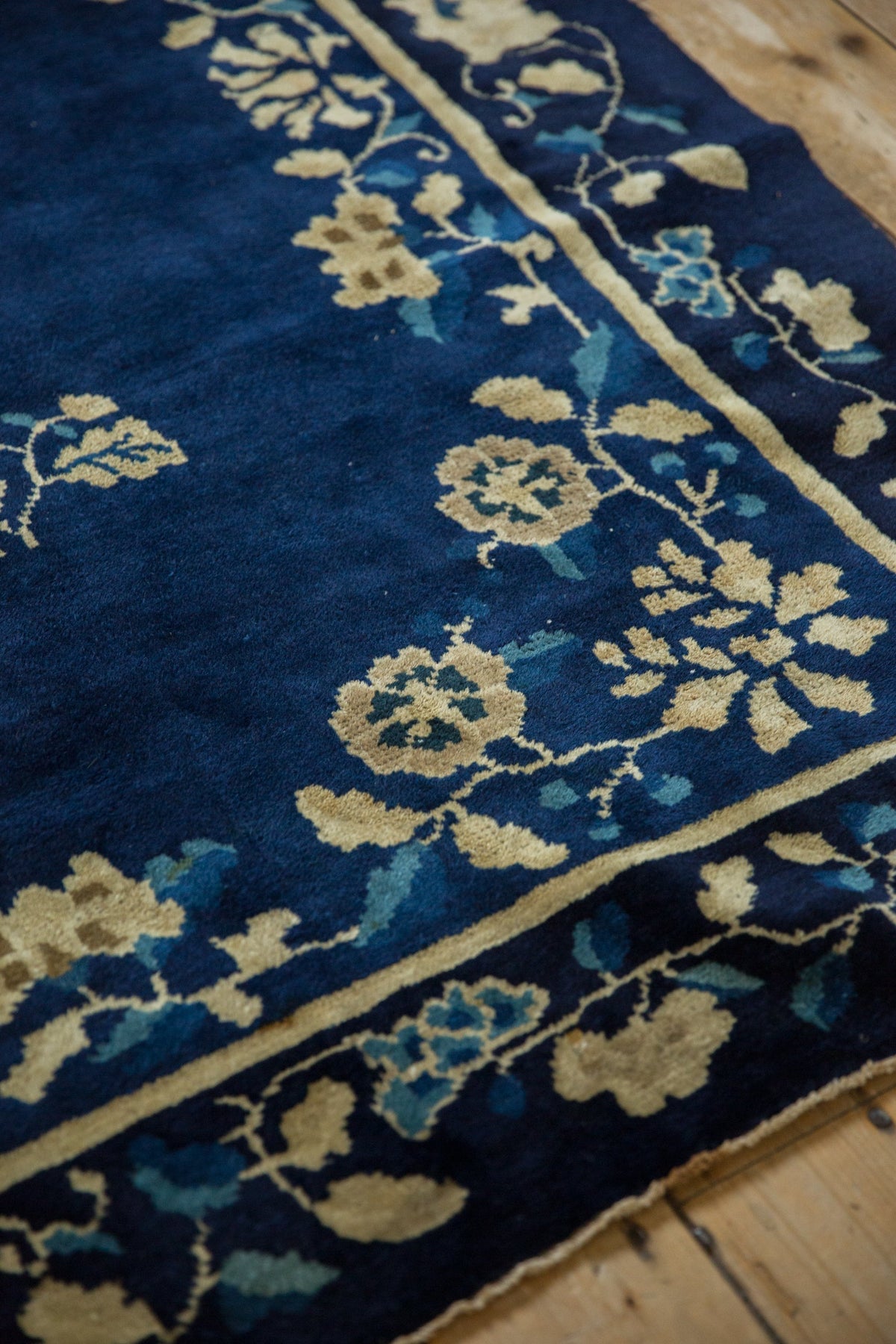 Close-up of a blue floral patterned rug on a wooden floor.